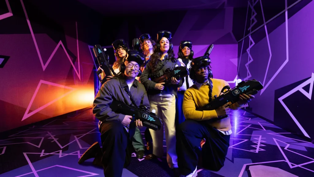 Team of coworkers in VR gear posing together in the free-roam VR arena